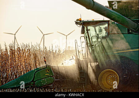 JOHN DEERE S680 HARVESTING CORN WITH WIND TURBINES IN THE DISTANCE Stock Photo