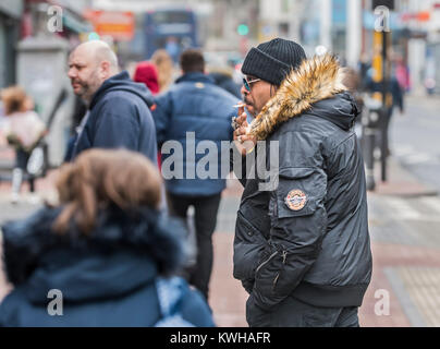 Black man dressed in Winter clothes smoking a cigarette in Winter in England, UK. Stock Photo