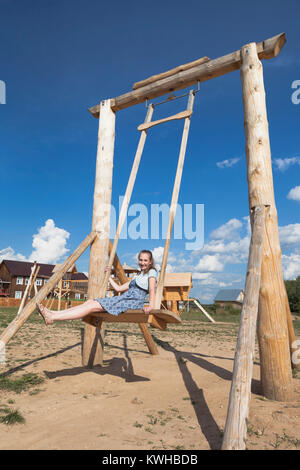 Girl swinging on wooden the seesaw at the playground Stock Photo