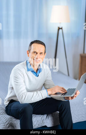 Pleasant man posing while using laptop Stock Photo