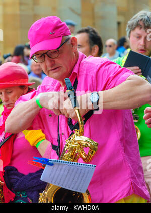 Male musician playing a baritone saxophone  in the Carnival of The Edinburgh Jazz and Blues Festival travelling down The Mound towards Princes Street Stock Photo