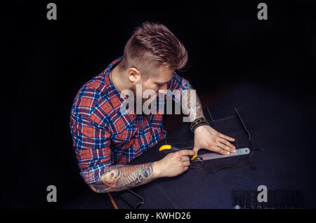 Artisan working with leather creates a new leather product  Stock Photo