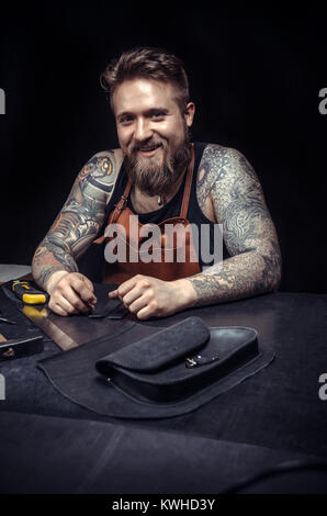 Professional Leather Worker at work on his new leather product in the shop Stock Photo