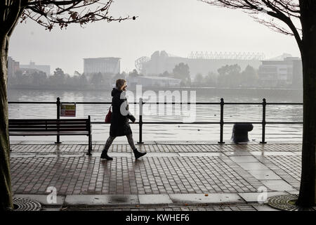 A dull , wet, foggy day Old Trafford stadium, home of Manchester United Football Club seen across the Ship Canal from Salford Quays Stock Photo