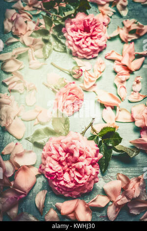 Pink roses composing with flowers petal and leaves on turquoise  shabby chic background, top view, retro toned, vertical Stock Photo