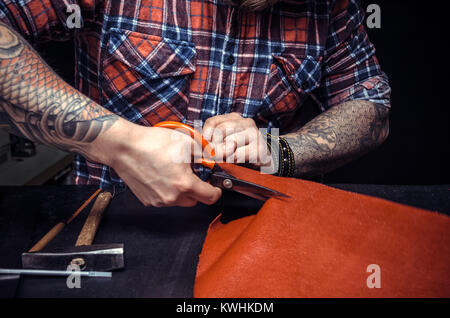 Man working with leather using crafting scissors Stock Photo