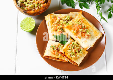Traditional Mexican dish - chimichanga. Corn cake with minced meat, pepper, onion, garlic, oregano, zira and guacomole sauce from avocado Stock Photo