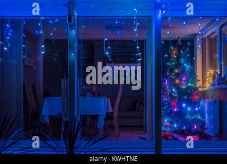 Outside view of living room with Christmas tree and dining table laid out for Xmas eve meal. Stock Photo