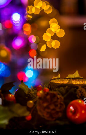 Christmas garland with candle and tree lights in background, festive warm ambience. Stock Photo