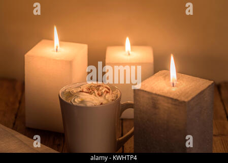 Warm cosy candlelit table with a mug of creamy hot chocolate. Stock Photo