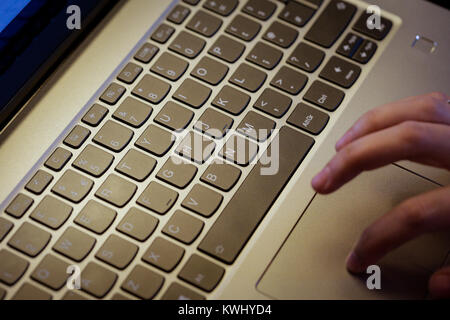 Young man uses laptop to electronically pay bills with his credit card Stock Photo