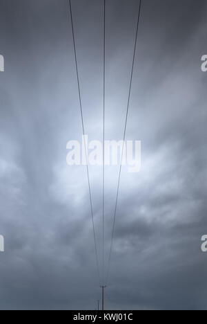 Electricity transmission lines  transferring electrical energy on a stormy cloudy sky Stock Photo