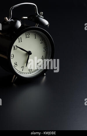 Black alarm clock on black background. Stock Photo