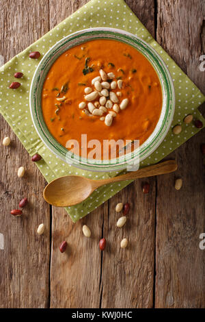 Peanut puree soup with greens close-up on a plate on a table. Vertical top view from above Stock Photo