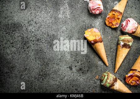 Different fruit ice cream in waffle cups. On a rustic background. Stock Photo