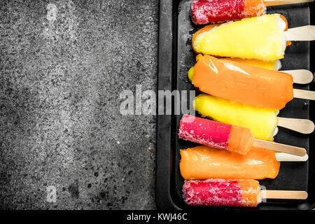 Multicolored fruit ice made from fruits. On a rustic background. Stock Photo