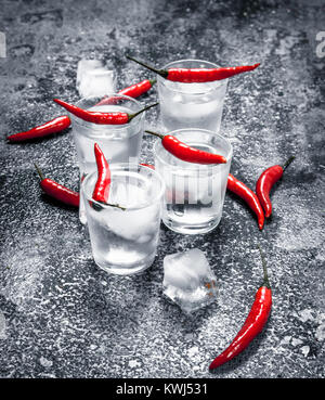 Vodka shots with hot peppers. On a rustic background. Stock Photo