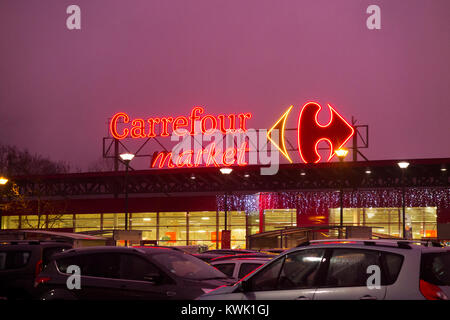 Carrefour French supermarket shop logo & name on display on the front of the shop building in France, during the early evening / dusk / night / sunset Stock Photo