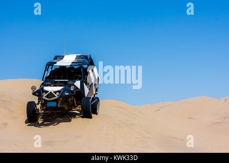 Dune buggy over a sand dune with blue sky in the desert, Huacachina, Ica, Peru Stock Photo