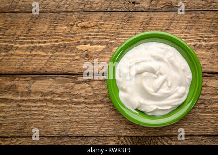 live organic Greek yogurt with vanilla in a green ceramic bowl against rustic wood Stock Photo