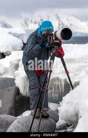 Photographer with huge telephoto lens capturing wildlife; Half Moon Island; Antarctica Stock Photo