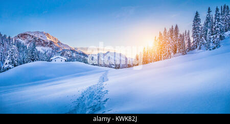 Panoramic view of beautiful winter wonderland mountain scenery with traditional mountain cabin the background in the Alps at sunset Stock Photo