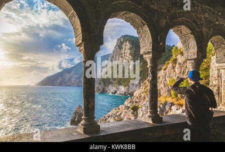 Young man enjoying scenic ocean view during sunset at famous gothic Church of St. Peter (Chiesa di San Pietro) in Porto Venere, Liguria, Italy Stock Photo