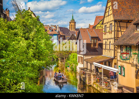 Historic town of Colmar, also known as Little Venice, with tourists taking a boat ride along traditional colorful houses in summer, Alsace, France Stock Photo