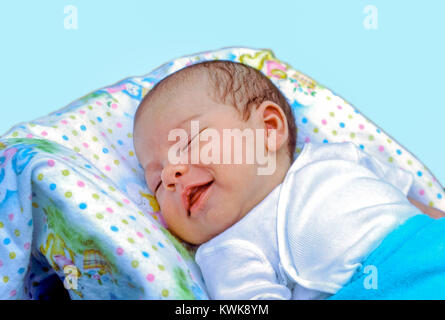 A newborn baby boy laying in his bed sleeping has a big smile on his face at home in Hudson, Massachusetts, United States. Stock Photo