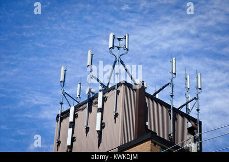 Cell phone antennas on the top of a building in the bight sun Stock Photo
