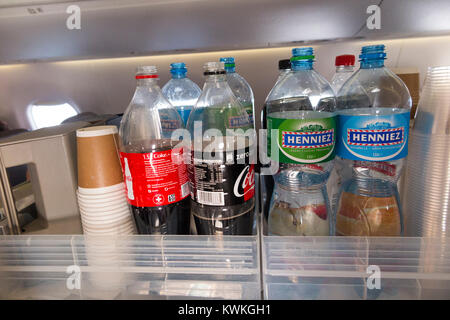 A drink trolley in the aisle on an Embraer 190 plane / aeroplane / airplane. Cabin crew are serving soft drinks to passengers during a flight. Stock Photo