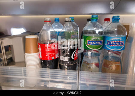 A drink trolley in the aisle on an Embraer 190 plane / aeroplane / airplane. Cabin crew are serving soft drinks to passengers during a flight. Stock Photo