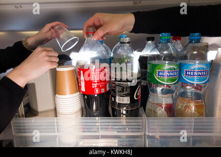 A drink trolley in the aisle on an Embraer 190 plane / aeroplane / airplane. Cabin crew are serving soft drinks to passengers during a flight. Stock Photo