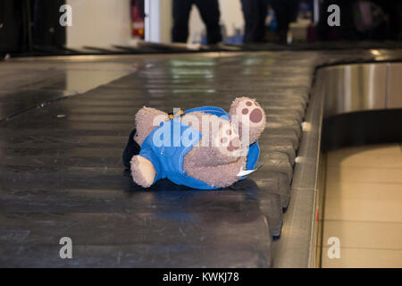 Child's soft toy, a Paddington Bear – possibly lost –  riding luggage claim / baggage reclaim carousel conveyor belt at London City Airport. UK. (93) Stock Photo