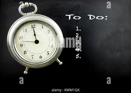 Pewter antique alarm clock on blackboard with To Do list in white chalk. Stock Photo