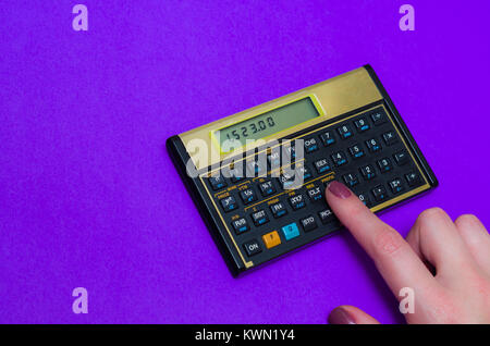 woman hand using financial calculator on vibrant blue background, great concept of finance, woman calculating. Stock Photo
