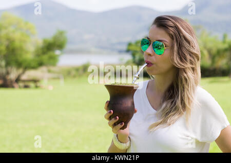 Blonde woman drinking the traditional Chimarrão from the State of Rio Grande do Sul in Brazil. Culture Gaúcha, Brazil. Stock Photo