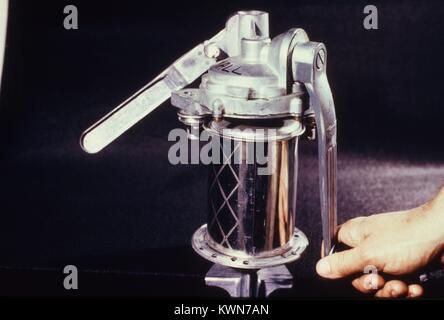 Close-up of the hands of a scientist using a manual canning device to seal a virus sample in a can in preparation for shipping to a research center, 1974. Image courtesy CDC. () Stock Photo