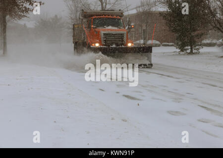Snow-removing machine cleans the street of the city park from the snow in the morning snow-covered trees. Cleaning road from snow storm. Stock Photo