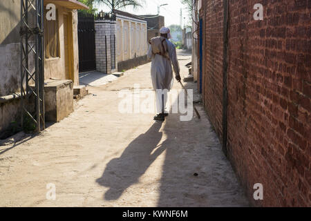 Rear view of an old Pakistani man walking in an alley