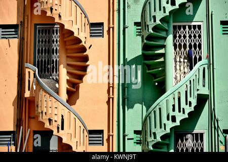 A pair of colorful old stone spiral staircases on the exterior of terraced shop houses in historic Little India, Singapore Stock Photo