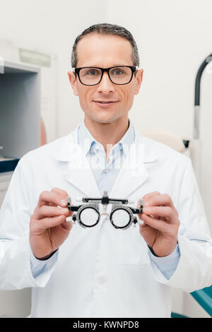 portrait of optometrist in white coat holding trial frame in hands in clinic Stock Photo