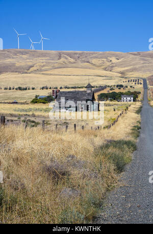 Abandoned church and wooden house in a prairie field behind a fence next to a American highway in Washington state, USA Stock Photo