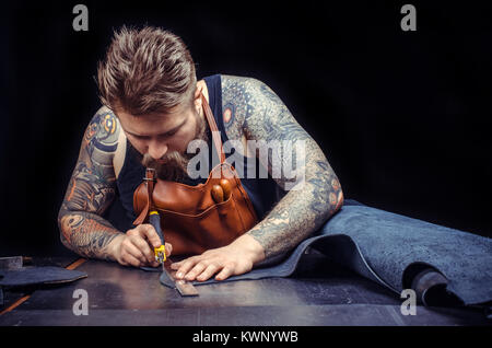 Man working with leather processes a workpiece from leather in the place of work Stock Photo