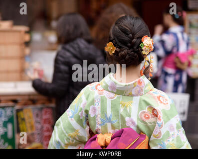 Japanese girl in colorful yukata kimono with a pretty hairstyle and intricate colorful hair ornament Kanzashi, rear view closeup. Kyoto, Japan. Stock Photo