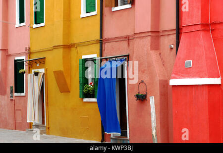 Beautiful colorfully painted homes on the island of Burano in the Venice lagoon, Italy.  Note the fabric covered doorways to cool the inside. Stock Photo