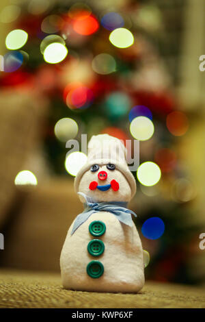 Handmade snowman made from a sock filled with rice and decorated with buttons with multicolor Christmas tree lights background Stock Photo