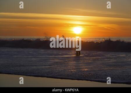 Isolated Lonely Fisherman on Torrey Pines State Beach north of La Jolla, California as sun sets behind Pacific Ocean Stock Photo