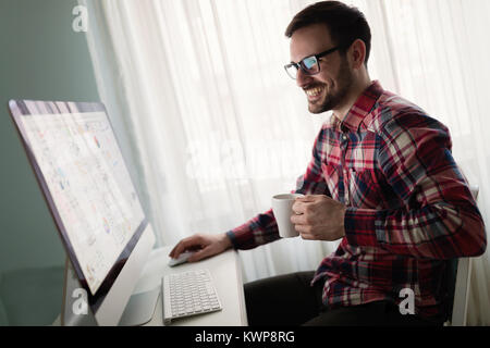 Young handsome designer working on project on computer Stock Photo