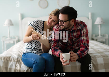 Young attractive couple using tablet in bedroom Stock Photo